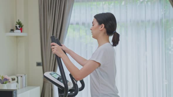 Asian Sporty young woman workout exercising by watching fitness live or video tutorial TV online. alt