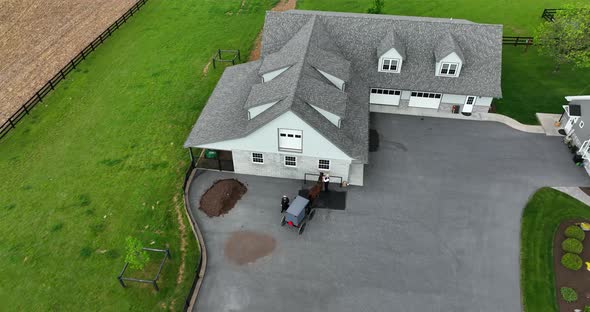 Aerial, top down approach of Amish couple tying up horse. Horse and buggy return home to Amish house alt