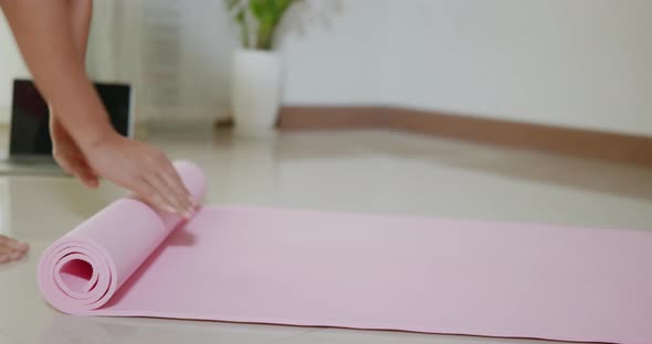 Woman yoga at home, female rolling up exercise pink yoga mat after exercising alt