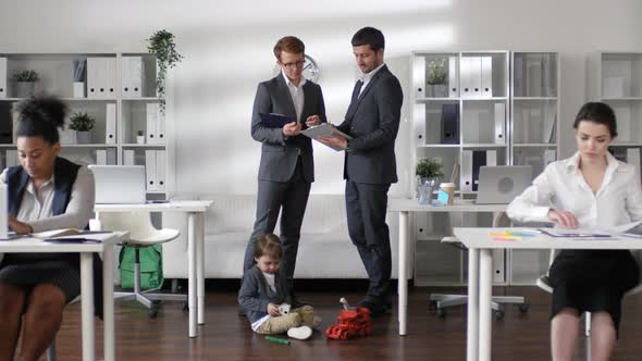 Cute Little Boy Playing in Office while Businesspeople Working alt