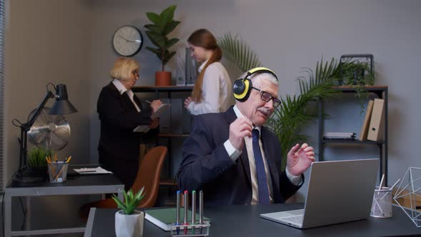 Happy Senior Business Man Entrepreneur Working on Laptop Listening Music on Headphones and Dancing alt