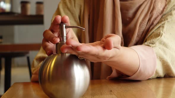 Young Women Using Hand Sanitizer in a Cafe alt