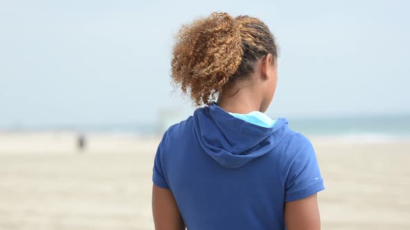 Close-up of a black woman beach volleyball player letting her hair down. alt
