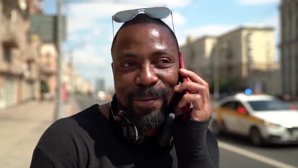 Black Man Is Chatting By Cell Phone on City Street, Closeup Portrait alt