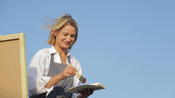 A professional artist paints a picture with oil paints. alt