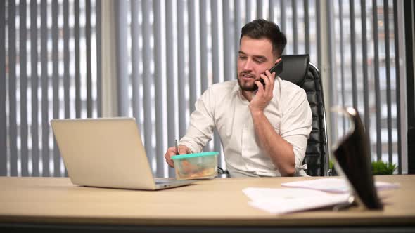 Manager is on the phone with his wife and is about to have a snack alt