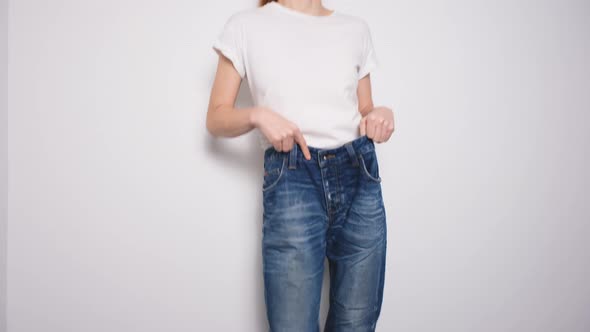 Happy Woman Dancing in Oversized Jeans on White Background alt