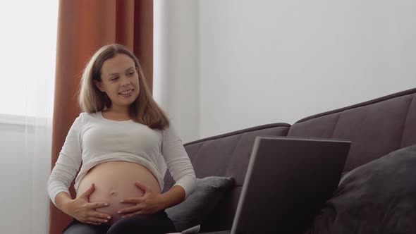 Pregnant Fairskinned Woman Communicates with Loved Ones Via Video on Laptop alt