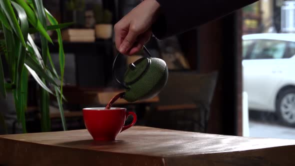Cinematic Slow Motion Pouring Herbal Tea in Red Cup from Green Tea Pot