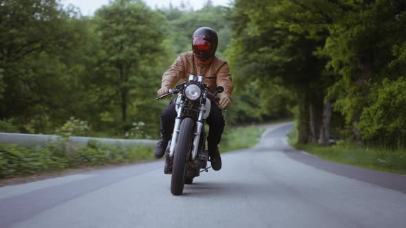 Tracking Shot of a Motorcycle on a Narrow Road Surrounded By Lush Forest Trees alt
