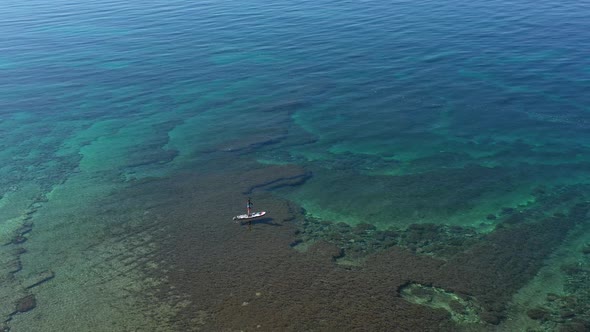 Woman Paddling on SUP Board in a Blue Sea.