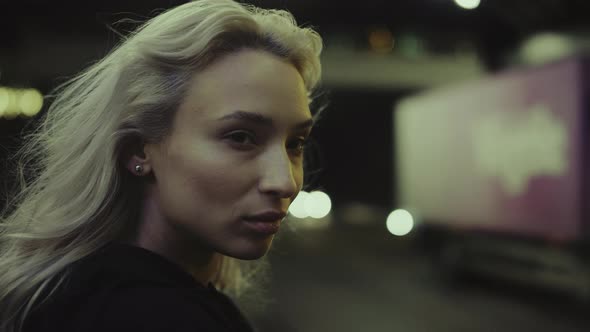 Blonde Lady Highway Night Looking Camera on Road with Driving Cars alt