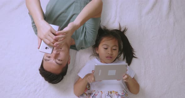 Father With Daughter Use Phone And Digital Tablet alt