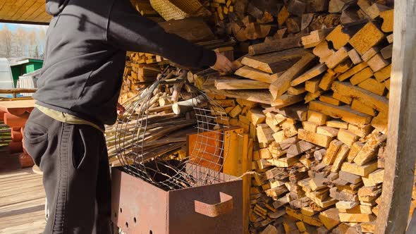 Male Farmer Puts Chopped Firewood From a Large Wood Wall Into a Carry Box in a Ukrainian Village alt