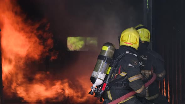 Two fireman or fire fighters try to extinguish flame of fire in room by using water sprinkler alt