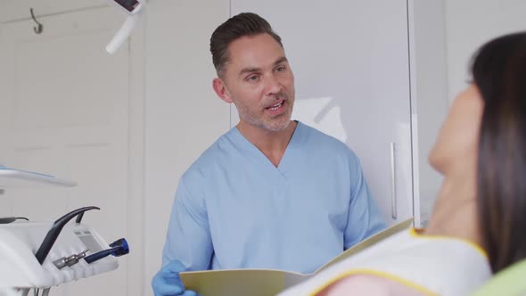 Caucasian male dentist talking and preparing female patient at modern dental clinic alt