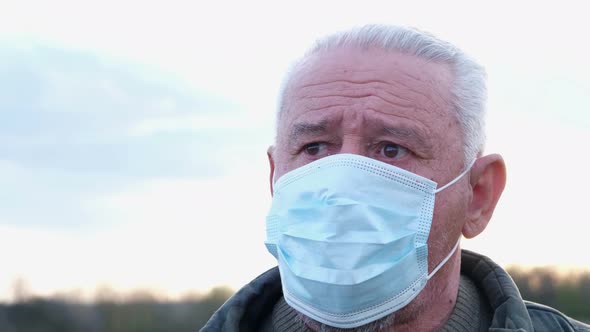 Worried Look of Grandfather in a Protective Medical Mask alt