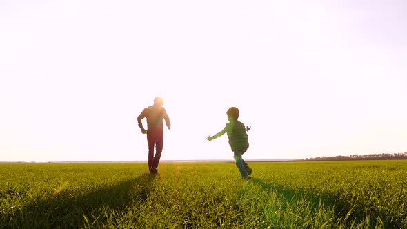 Happy Family: Dad and Son Play Running Through a Green Meadow, Launching a Plane Into the Sky alt