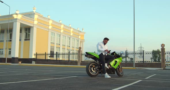 Man Sitting on Motorcycle and Using Smartphone in City