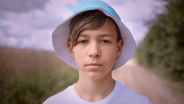Portrait of a Funny Boy Standing in Nature Near the Field and Looking at the Camera Cinematic Shot