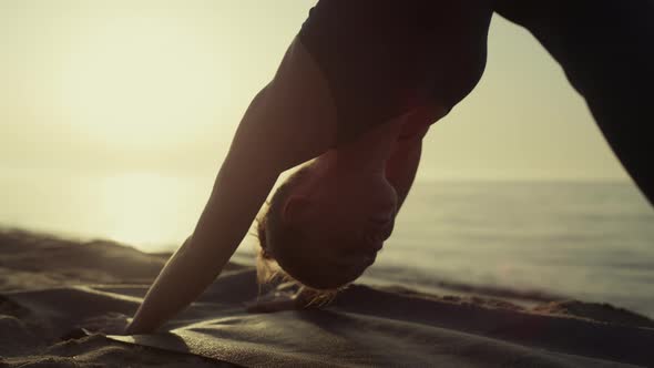 Yogi Girl Practicing Asana Standing Pose Down Face Dog on Sandy Beach Close Up alt
