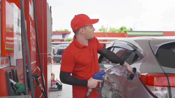 A Caucasian man, people, worker filling up fuel by using petrol pump at gasoline petrol station alt
