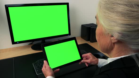 Old Caucasian Woman Works on Computer and Tablet in Home - Green Screen alt