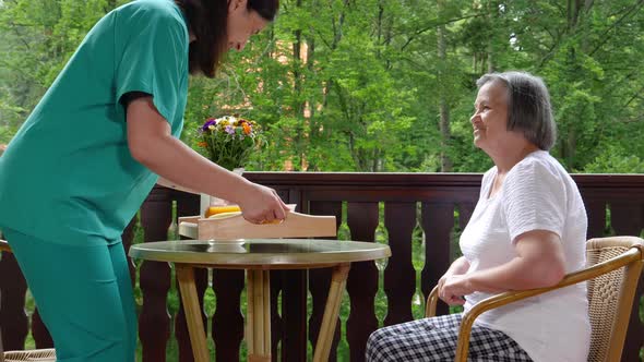 Healthcare Worker Serving Meal to Elderly 