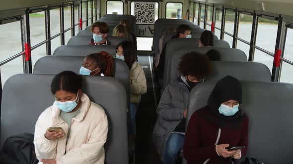Diverse Pupils in Masks Using Phones on School Bus alt