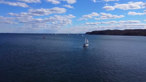 The yacht sails in the sea in blue water on a sunny day near the coast