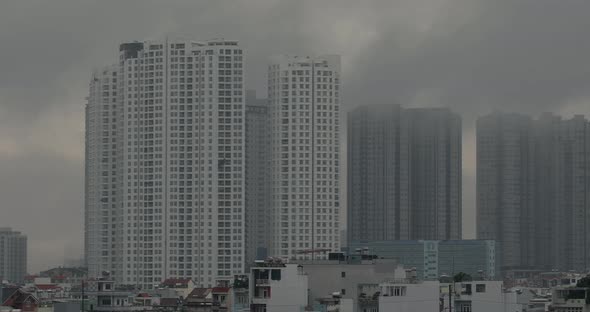 Atmospheric panning shot across large high-rise apartment buildings with morning fog, clouds or poll alt
