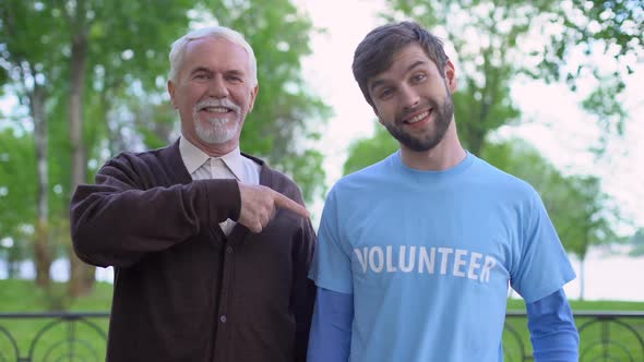 Male Pensioner and Social Activist Pointing at Volunteer Word on T-Shirt, Help alt