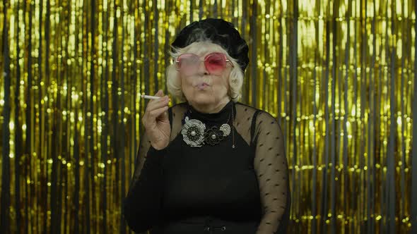 Elderly Style Mature Woman in Fashion Black Clothes in Sunglasses Posing, Smoke Cigarette alt