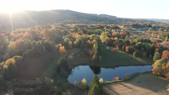 Aerial Drone Shot Flying Towards Hills and Farm with Pond and Fall Colors
