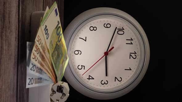 Closeup Shot of Cash on an Electrical Socket with a Clock Behind Them