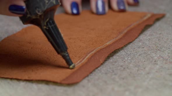 Closeup of Worker Hands Applying Glue on Edge of Leather Piece Indoors alt