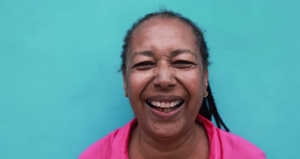 Senior african woman smiling on camera with blue background alt