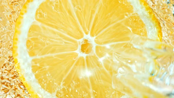 Super Slow Motion Shot of Splashing Water on Rotating Lemon Slice at 1000Fps alt