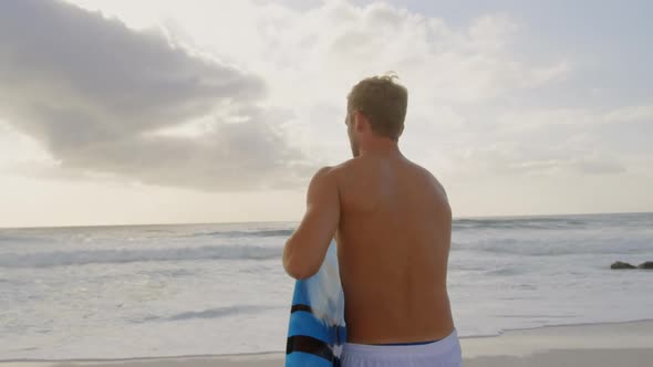 Man with surfboard on beach 4k