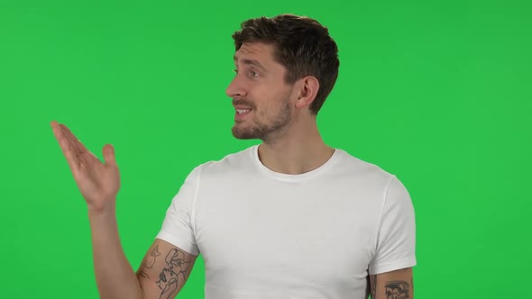 Portrait of Confident Guy Is Talking and Pointing Side Hand for Something, Copy Space.. Green Screen alt
