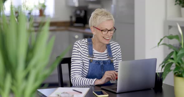 Mature woman making video call from home office