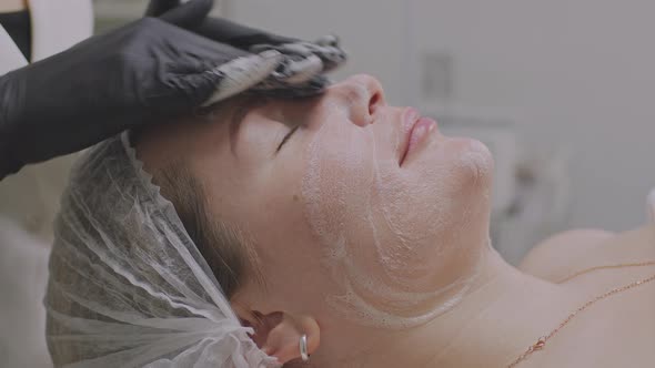 A Woman in a Beauty Salon Applies a Moisturizing Tissue Mask to Her Face