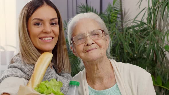 Portrait of Happy Woman Holding Bag of Groceries and Hugging Grandmother