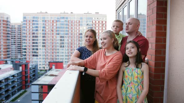 A Large Happy Family of Five People on the Balcony of a New Residential Complex Enjoy the View of