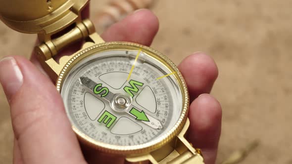 Man Hand Holding Gold Compass on Sand Background Closeup Golden Compass in Human Palm alt
