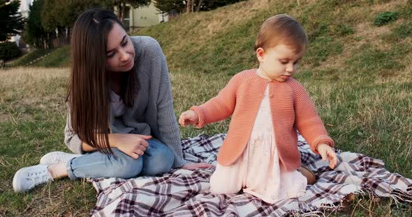 Mother and a Small Daughter, Spends Time Together in a City Park on a Picnic. Young Woman and Little alt