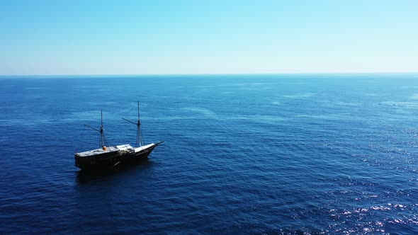 A large white and black ship alone in the middle of the beautiful blue waters of the ocean alt