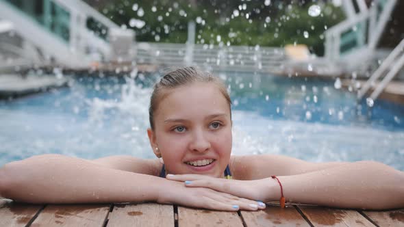 Portrait of a Smiling Teenage Girl with Dental Plates at the Edge of the Pool Closeup