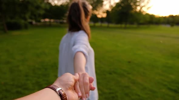 Follow me. Young unidentified slim girl leads her boyfriend by the hand