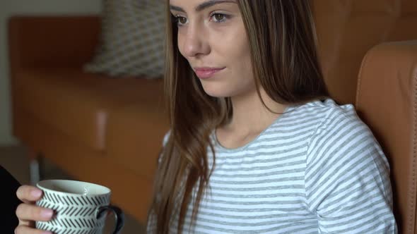 Beautiful young woman relaxing at home and drinking coffee alt